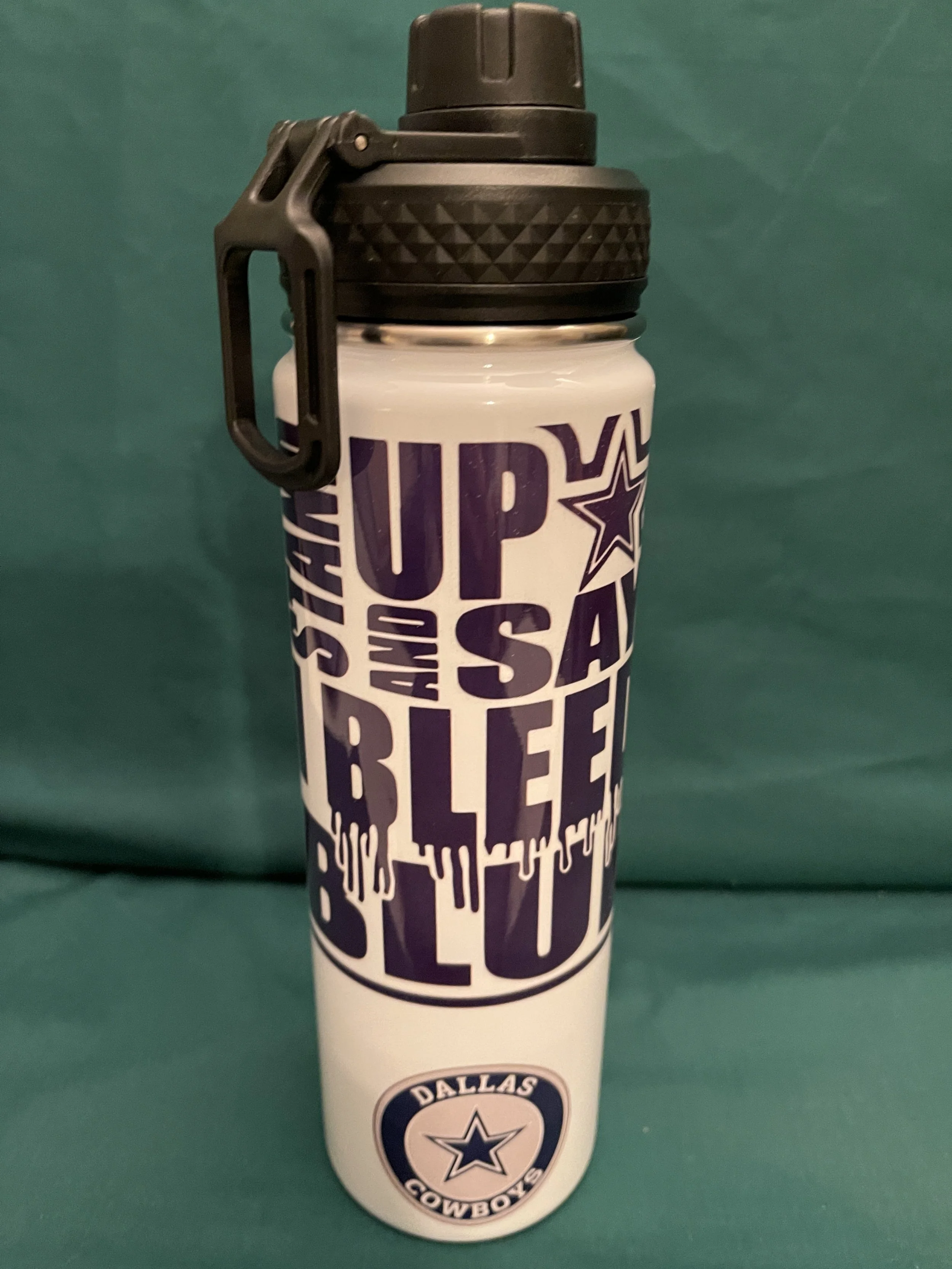 White water bottle with Dallas Cowboys logo and motivational text in black and purple, against a green background.