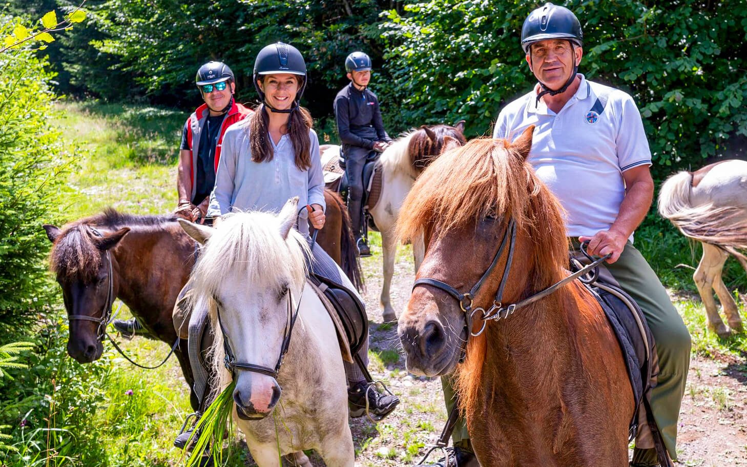 A group of horse riders are smiling while riding Icelandic horse during summer.