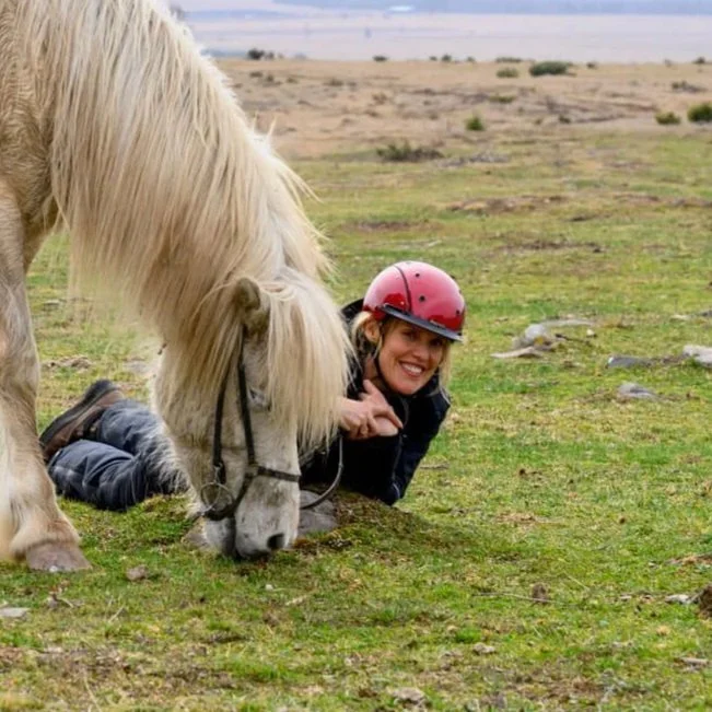 A woman smiles next to a white icelandic horse in Transylvania at Ivo Riding Hall