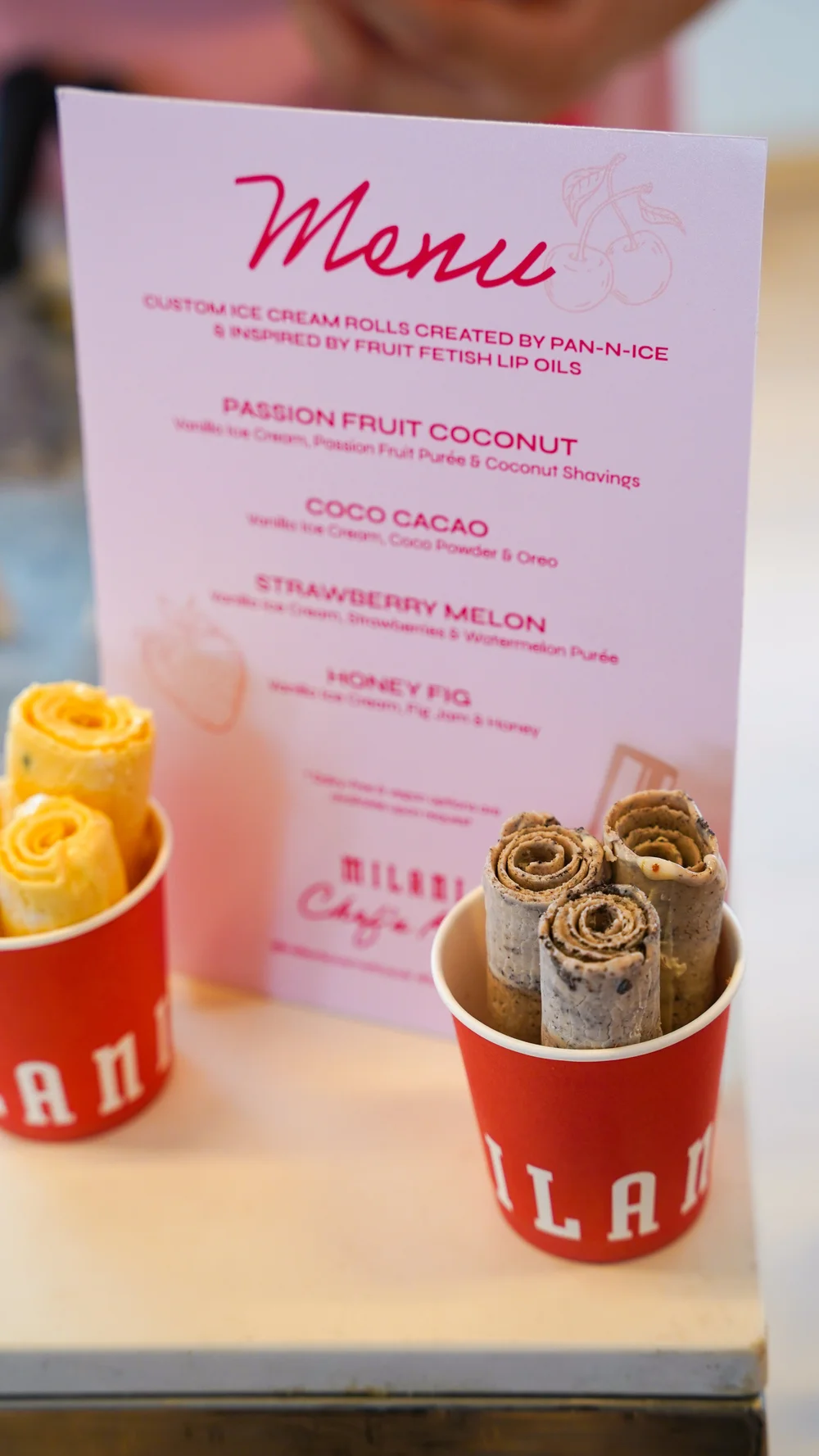 Milani branded cups of ice cream rolls displayed in front of the event menu