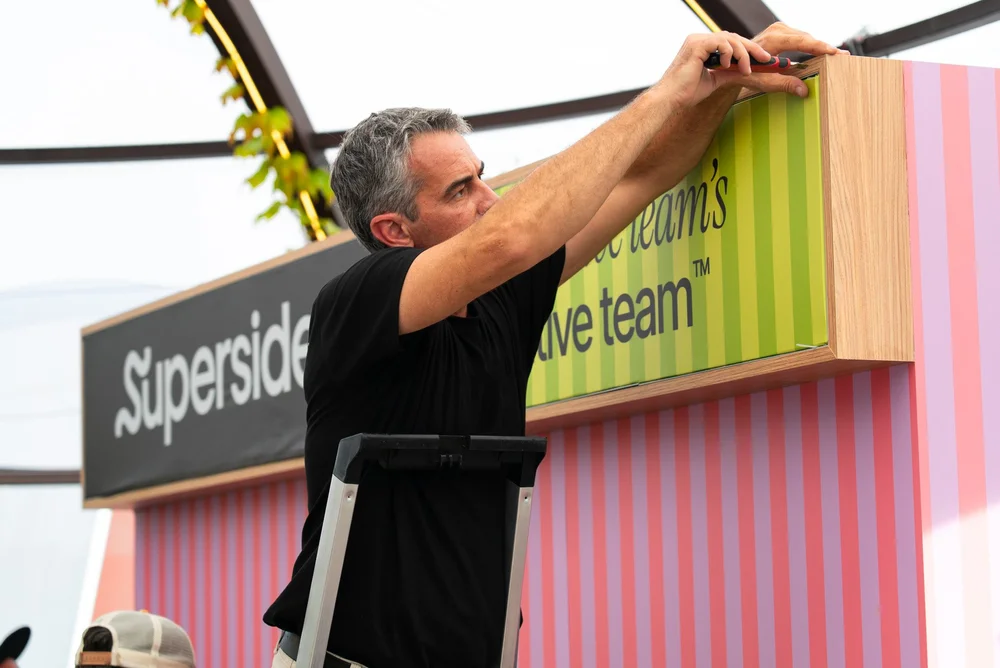 Rolling Minds team member fitting the branded fascia on the Superside Cannes stand