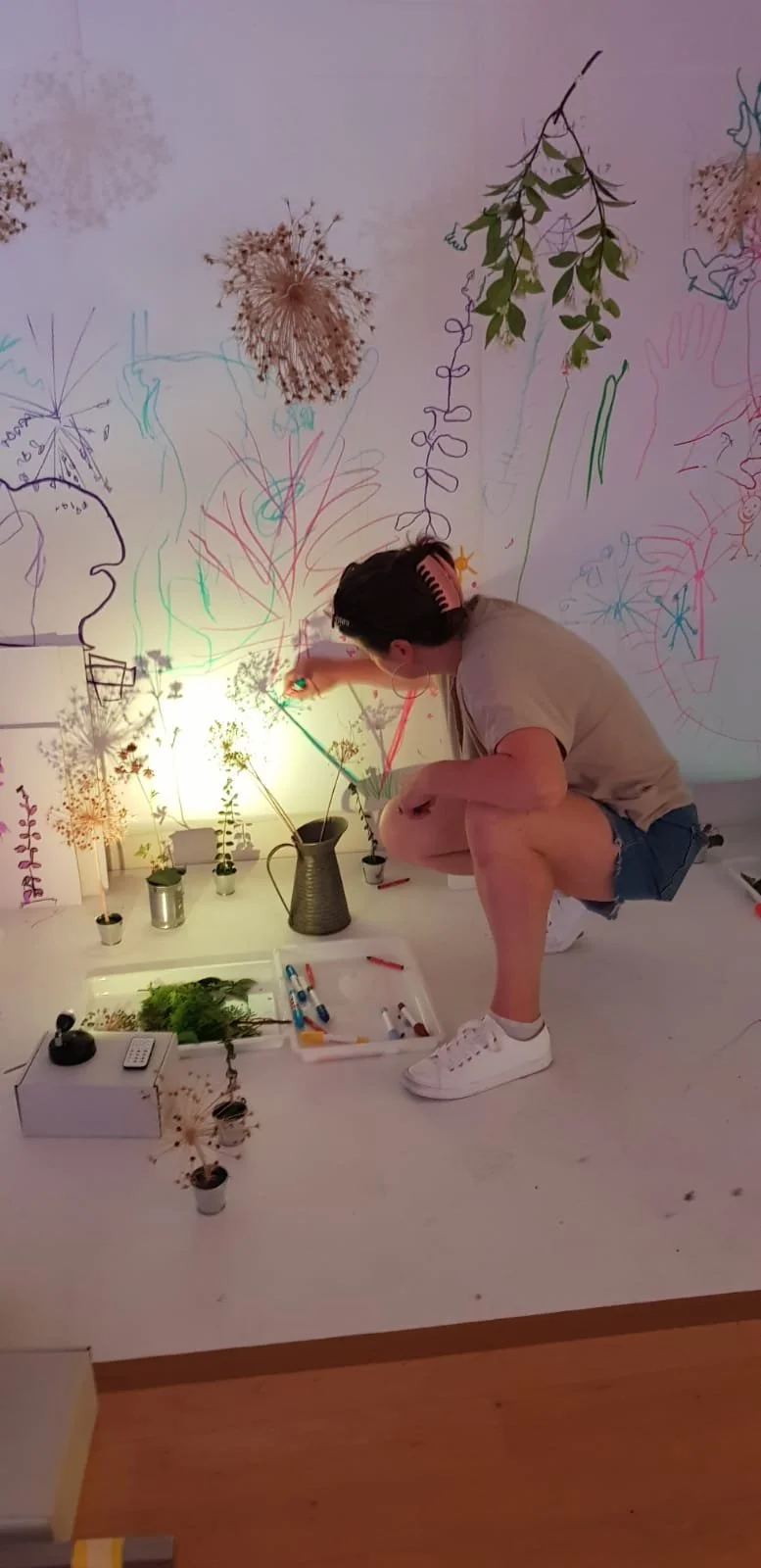 Light play with colourful markers, surrounded by  dried flowers, and wall art featuring botanical illustrations and line drawings.