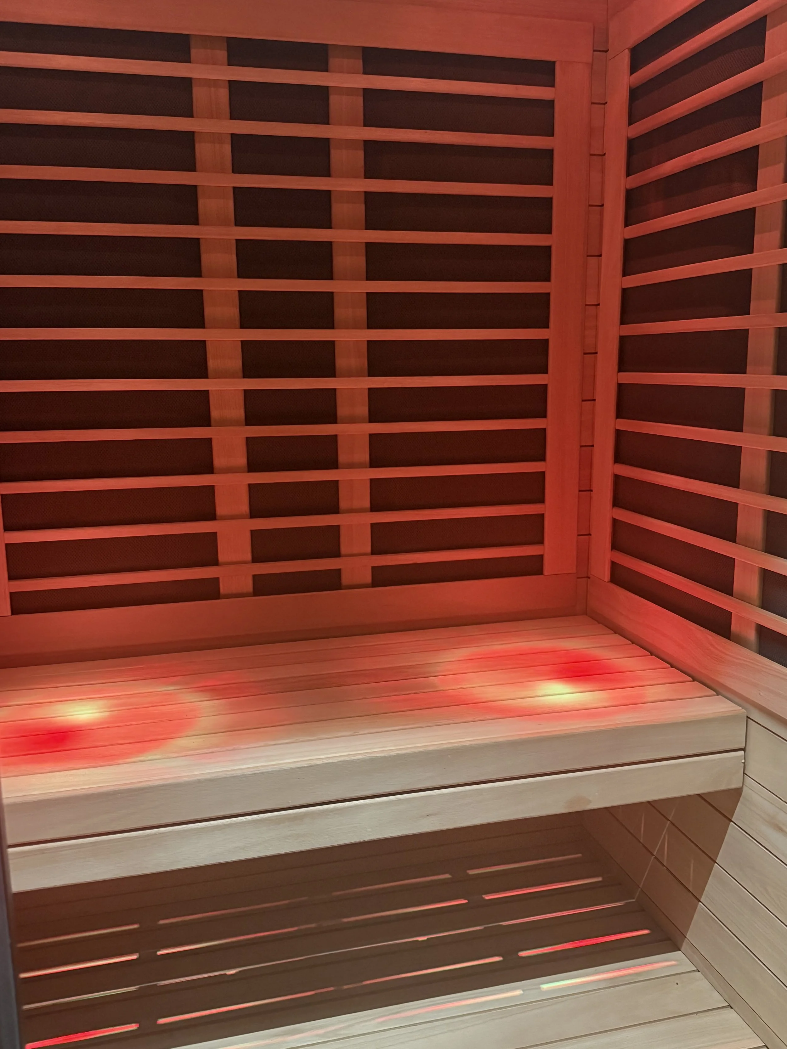 Luxury infrared sauna with wooden interior and red LED lights.