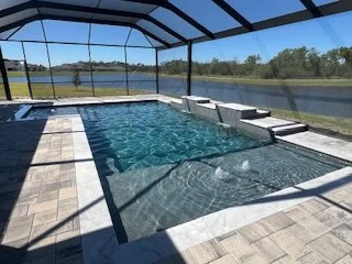 Screened-in backyard pool area with a relaxing pool and a scenic view of a lake or river outside.
