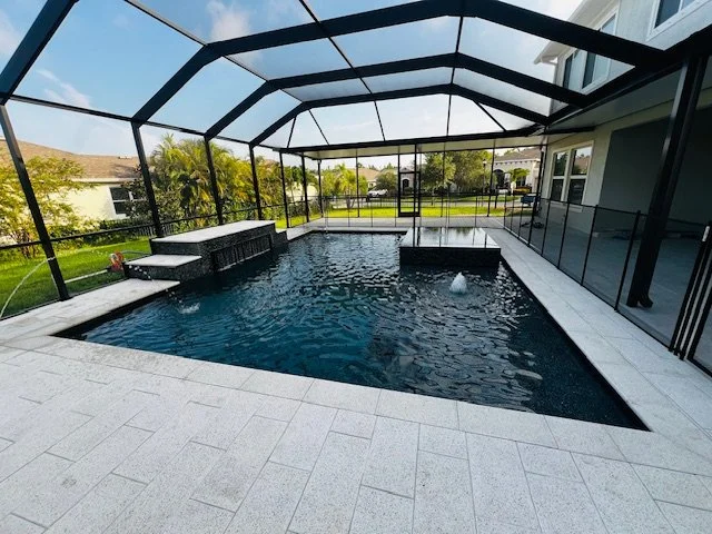 Enclosed backyard pool with a waterfall feature and a small fountain in a screened-in patio area.