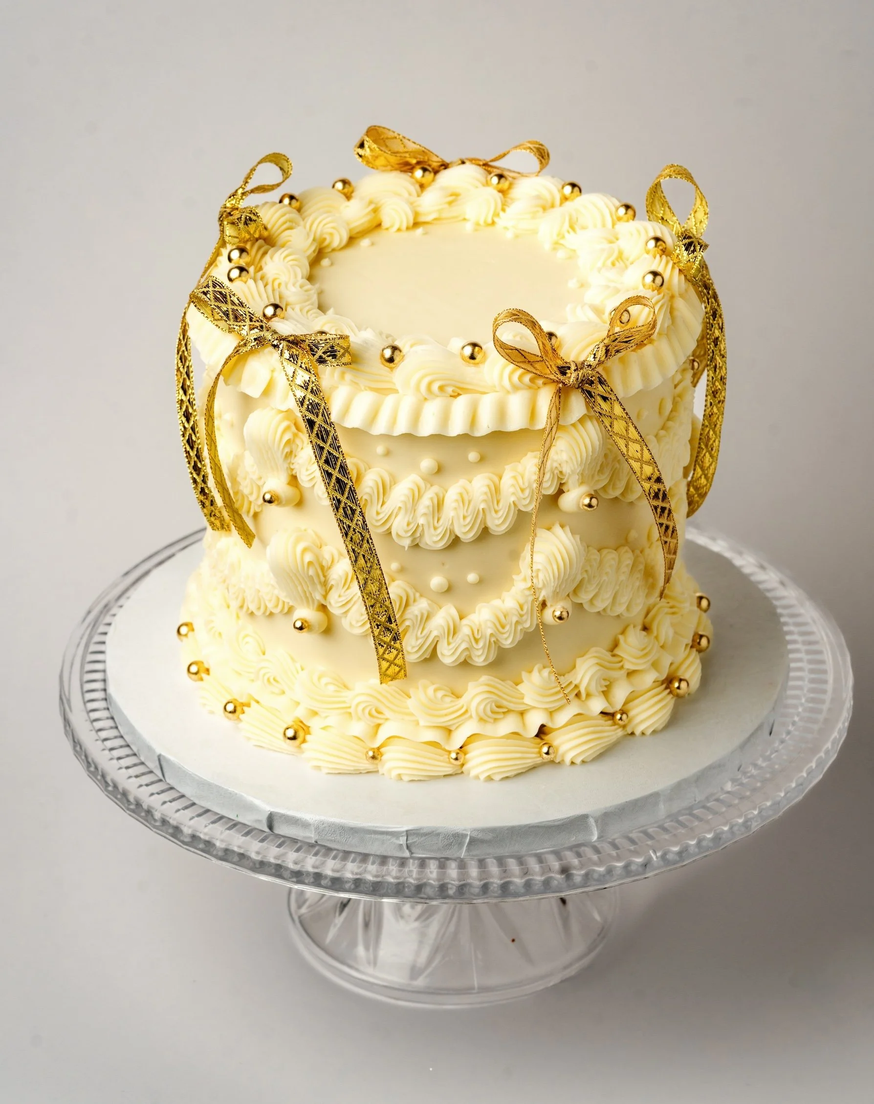 ECBG cake studio white cake with gold ribbons decorating it