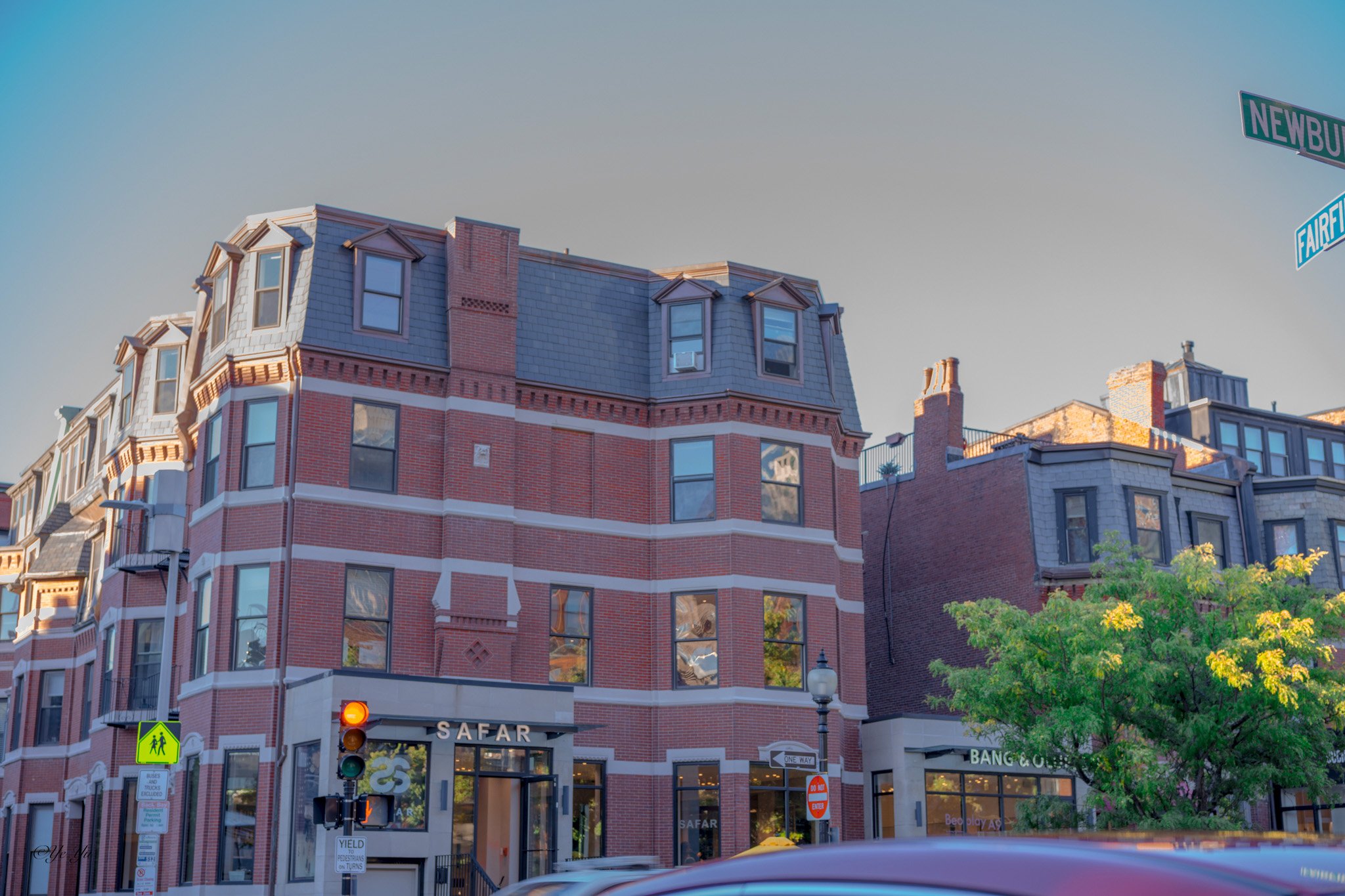Newbury Corner — Late sunlight falls on a red-brick corner building at Newbury and Fairfield streets in Boston.
