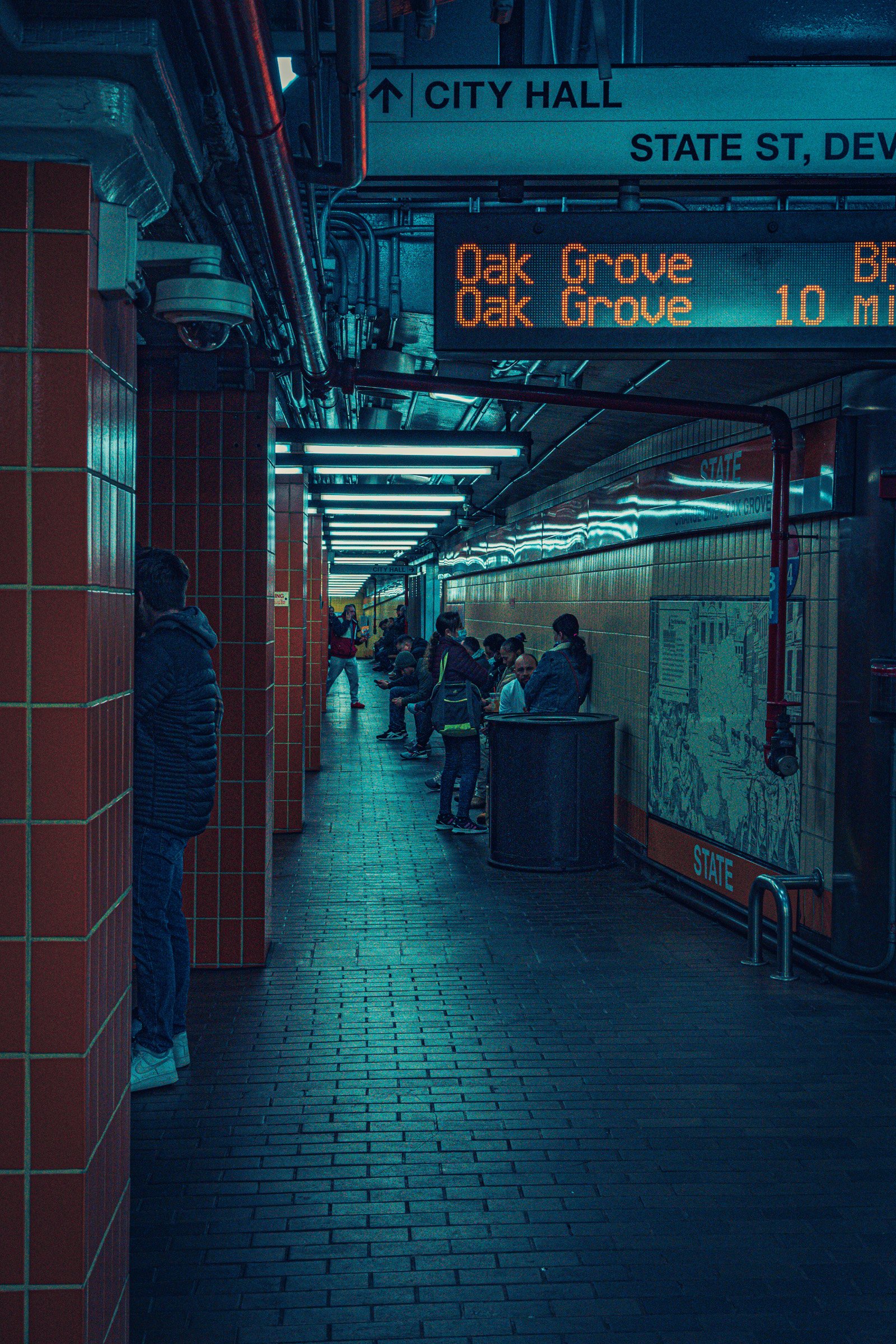State Street — Passengers wait along a tiled Boston subway platform beneath an orange Oak Grove sign.
