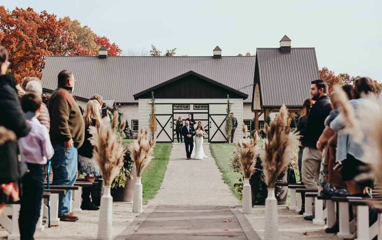 bride escorted down the aisle at indoor outdoor wedding venue in Michigan