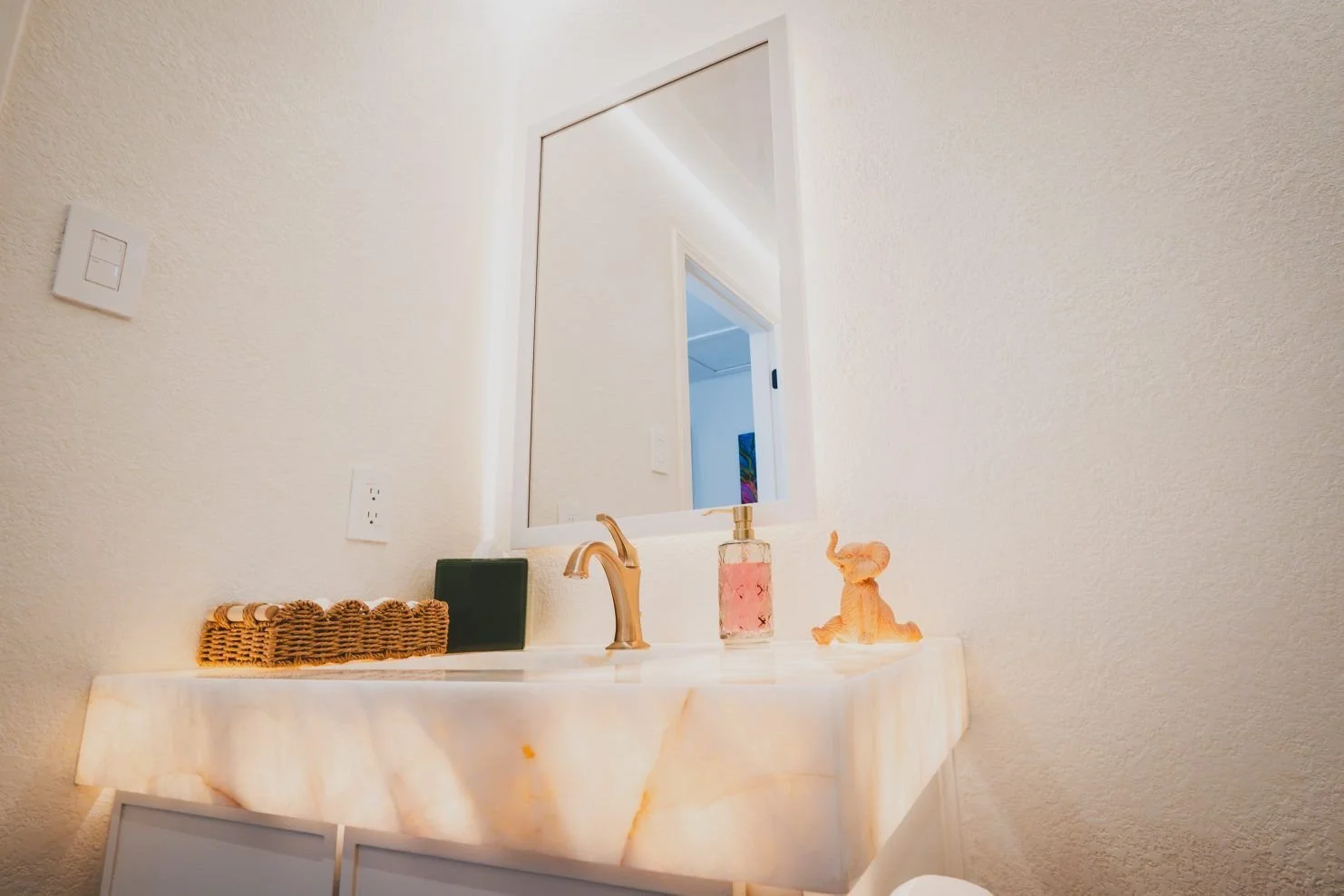 Powder room with glowing onyx vanity and cove lighting