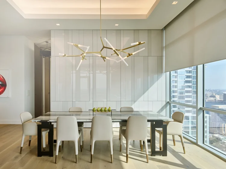 Dining room with chandelier and cove lighting (Seaholm Penthouse, Austin, TX): Ketra G2 linear fixtures, Ketra D2 downlights and HomeWorks QSX
