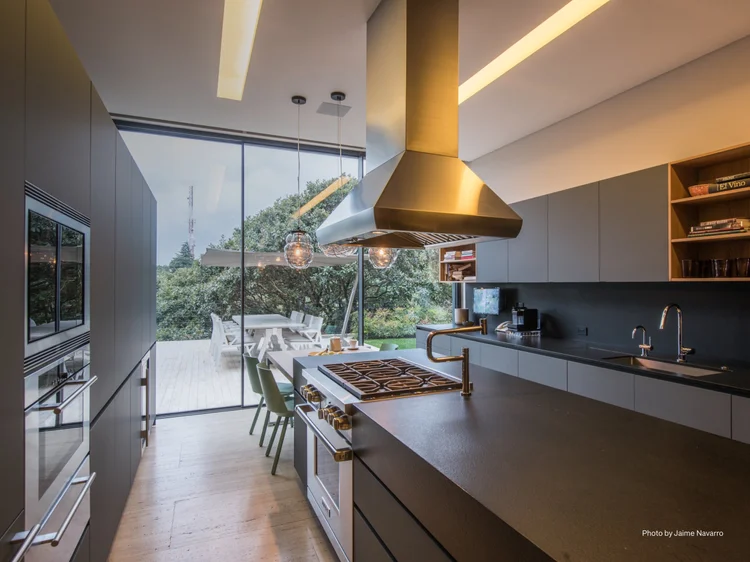 Kitchen opening to a patio (Latin America Residence): Lutron smart lighting with linear recessed fixtures and pendants