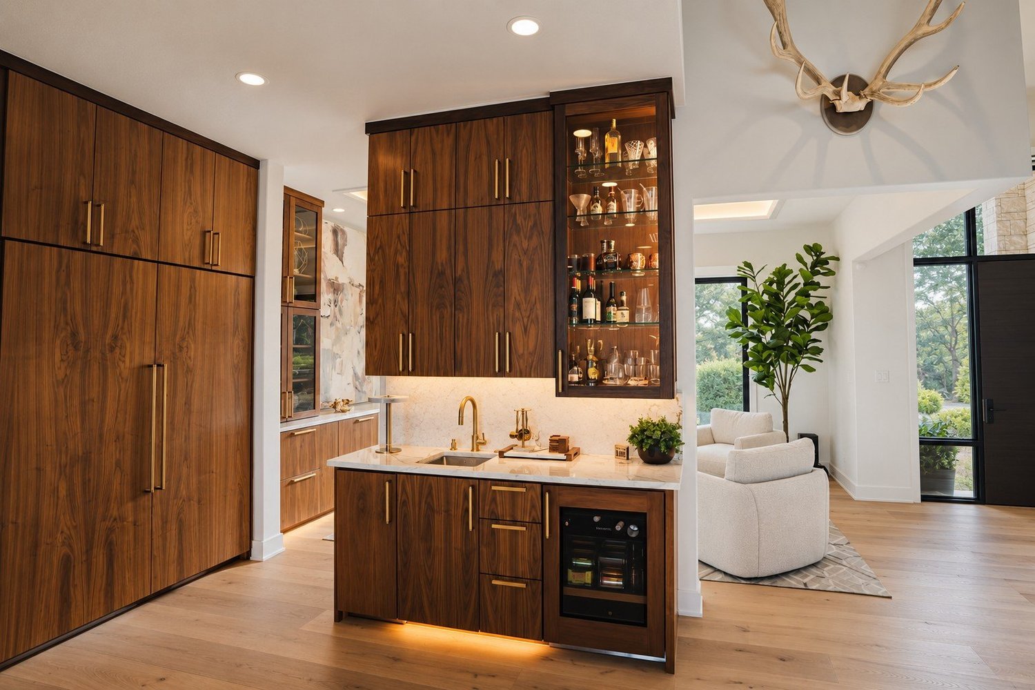 Walnut home bar with a lit glass display cabinet, brass hardware, and warm under-cabinet light