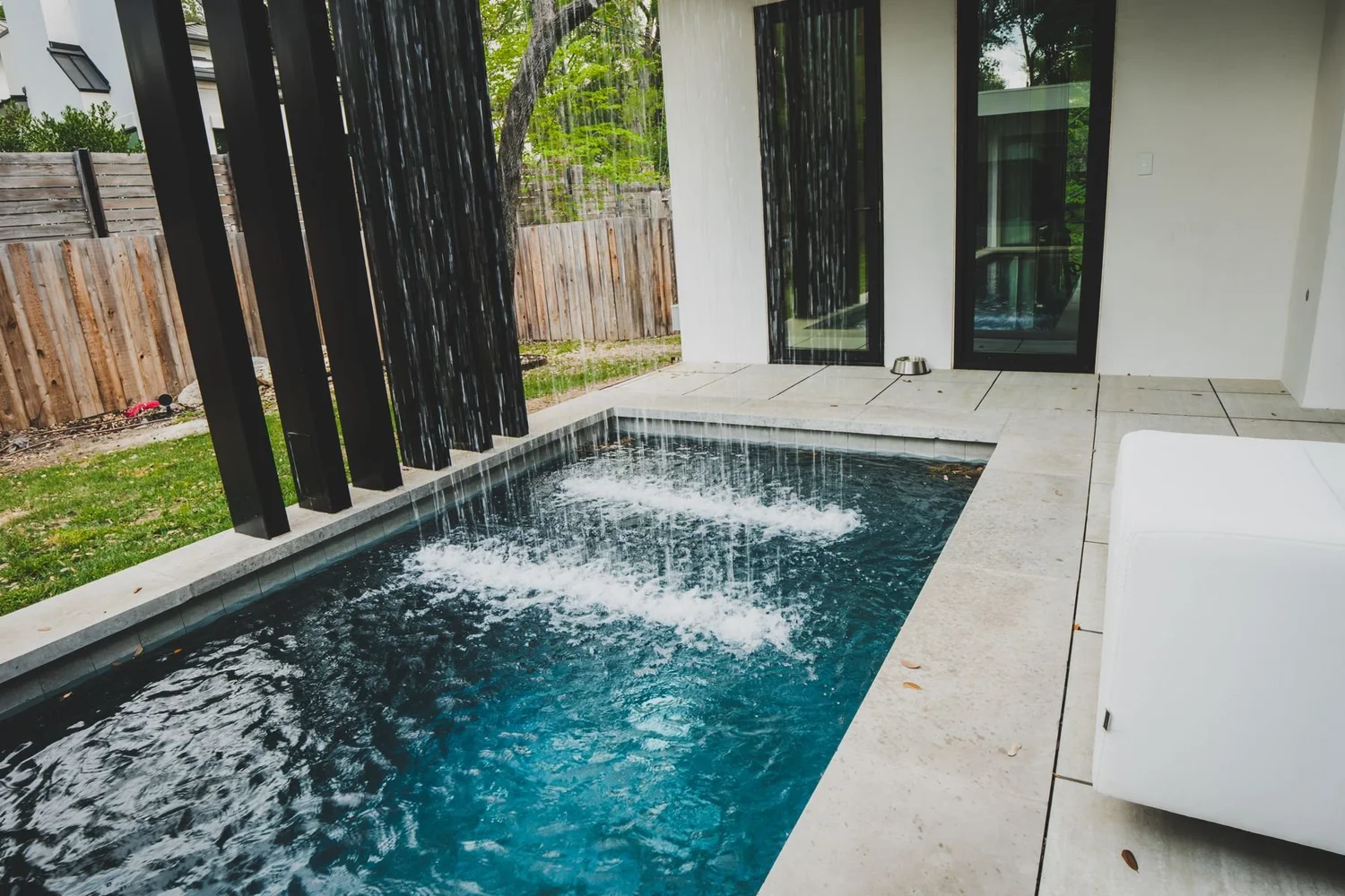Plunge pool and patio beside a modern home