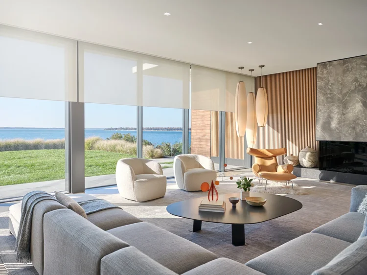 Waterfront living room with glass walls (Shady Island Residence): Lutron motorized roller shades and layered lighting