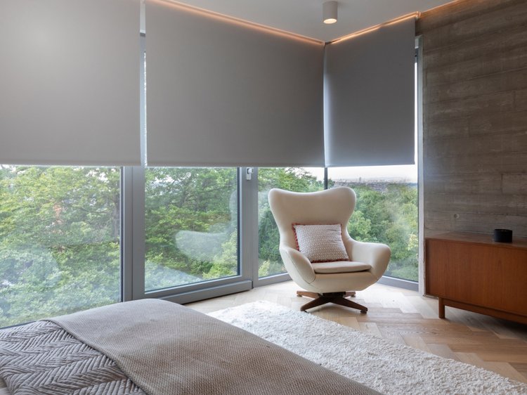 Bedroom with corner windows: Lutron motorized roller shades