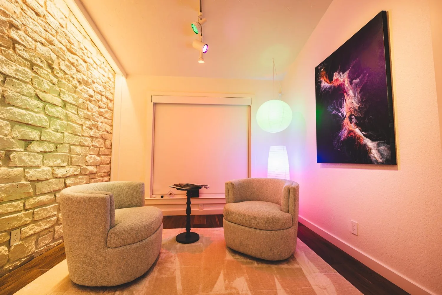 Showroom lounge with a stone wall, artwork, and Ketra lighting set to vivid color