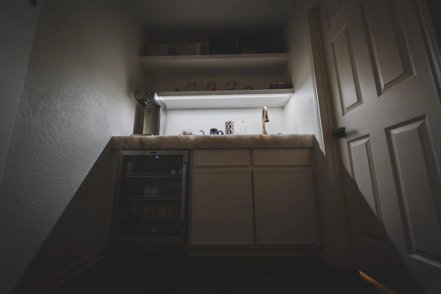 Wet bar with shelf and toe-kick lighting in a dimmed evening scene