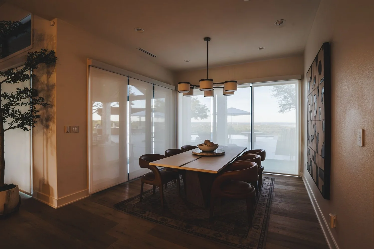 Dining room with sheer shades over sliding glass doors and a pendant light