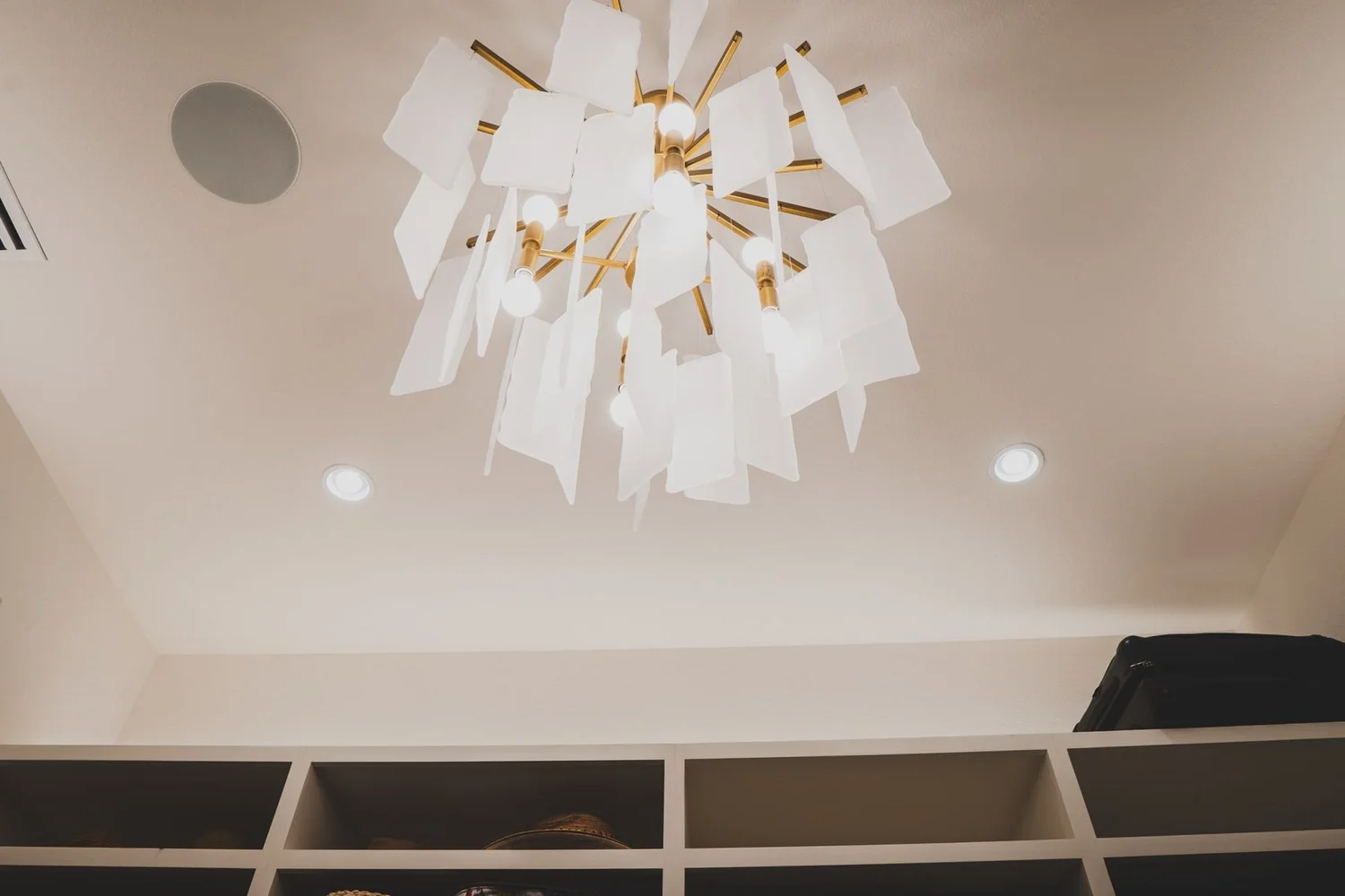 Sculptural chandelier above built-in shelving