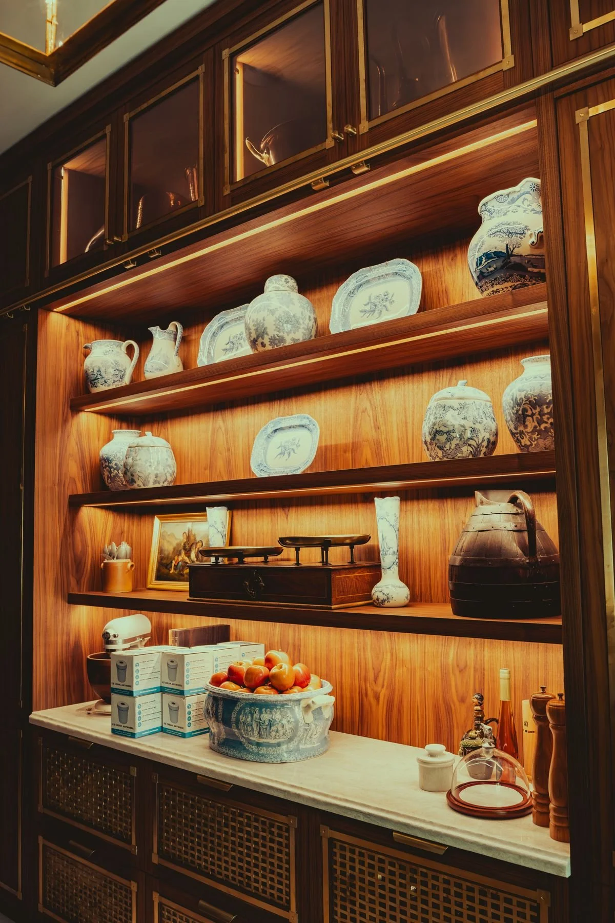 Pantry shelves with warm accent lighting behind china and glassware