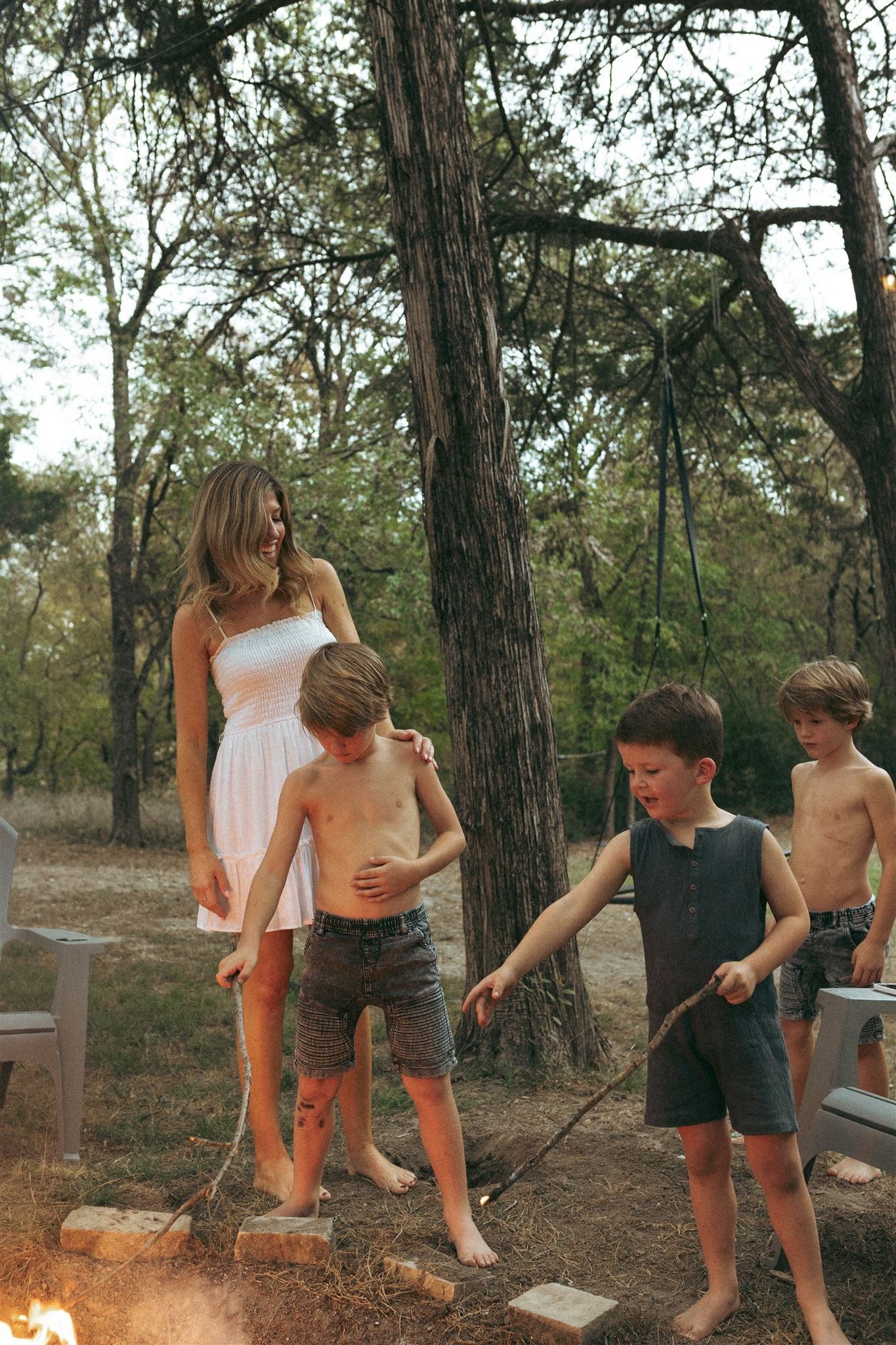  three boys with their mother outside by a fire in allen, texas during a family photography session 