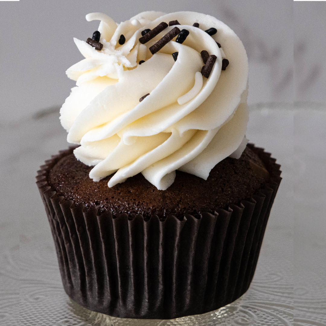 Chocolate cupcake topped with white buttercream frosting and chocolate and white sprinkles.