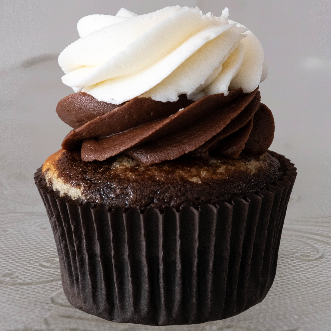 Chocolate and vanilla cupcake with swirls of white and brown frosting on top.
