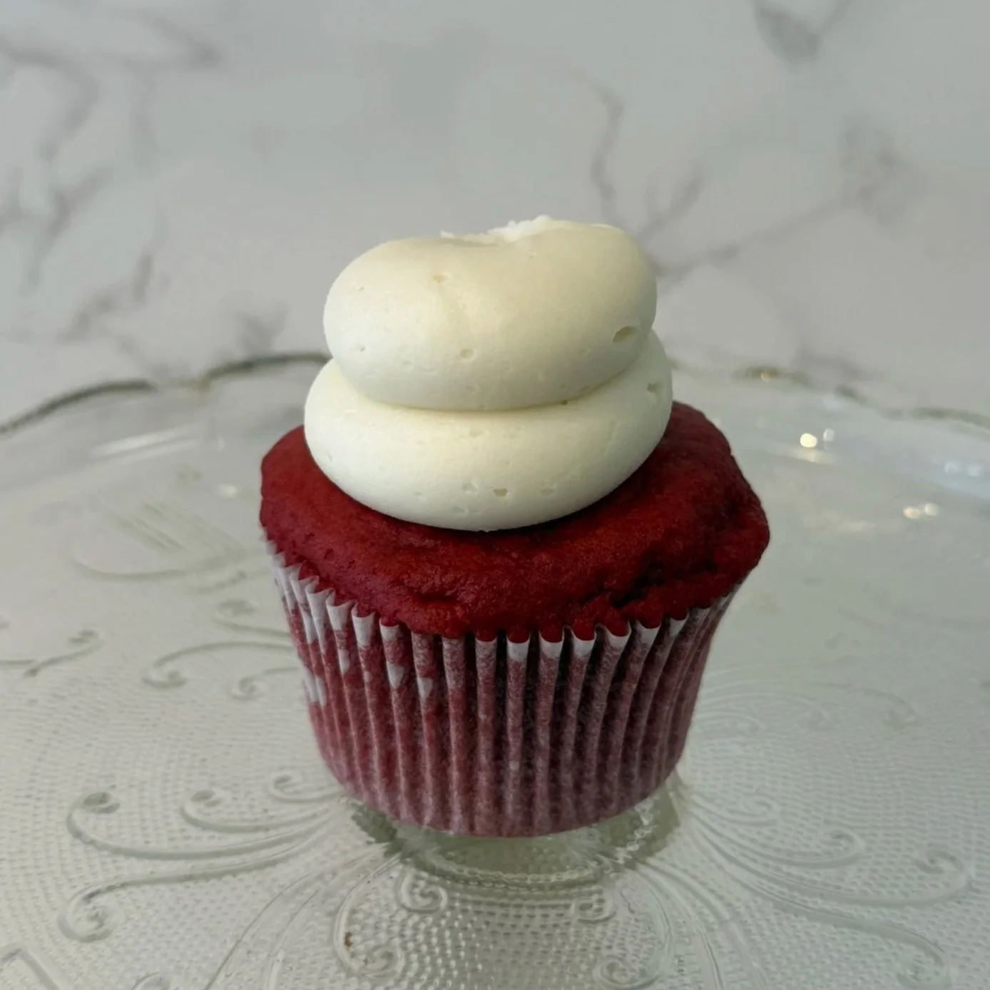 Chocolate cupcake with chocolate frosting on top against a white background.