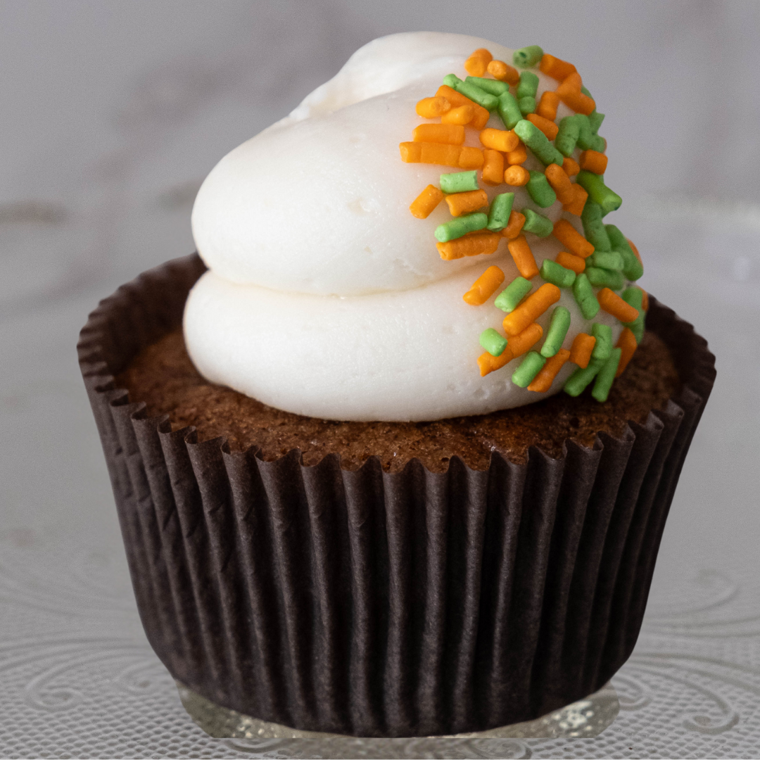 Chocolate cupcake with white frosting and orange and green sprinkles