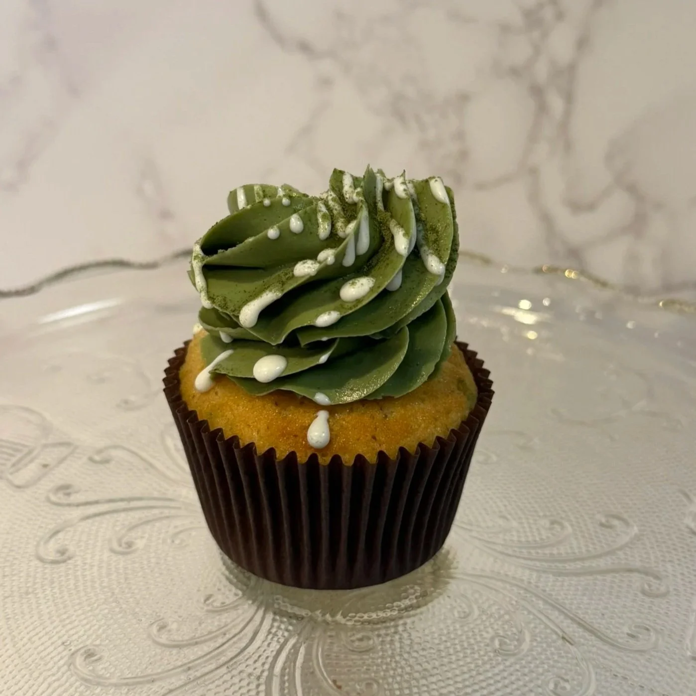 Cupcake with chocolate wrapper, topped with white frosting.