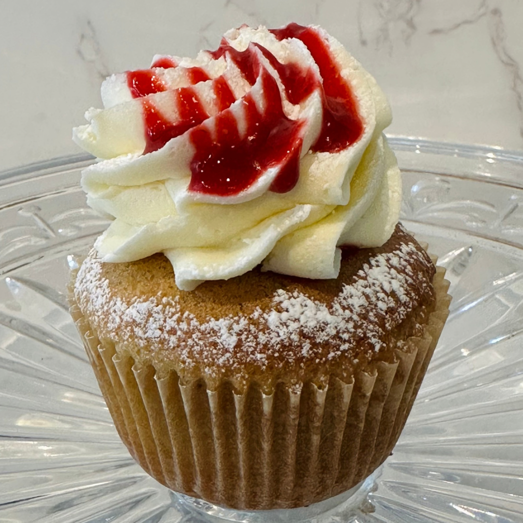 Chocolate cupcake with white frosting swirl on top, in a ridged paper liner.