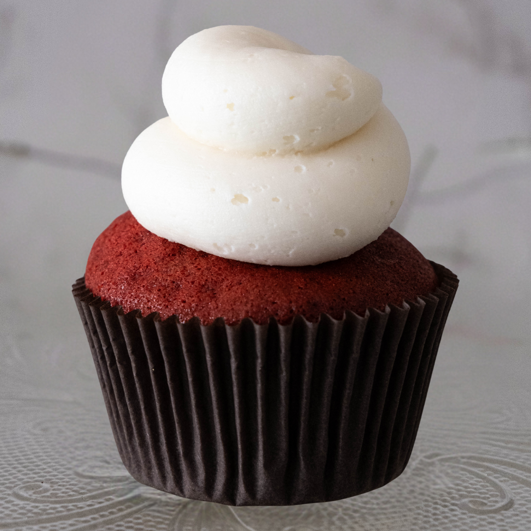 Red velvet cupcake with cream cheese frosting on top.