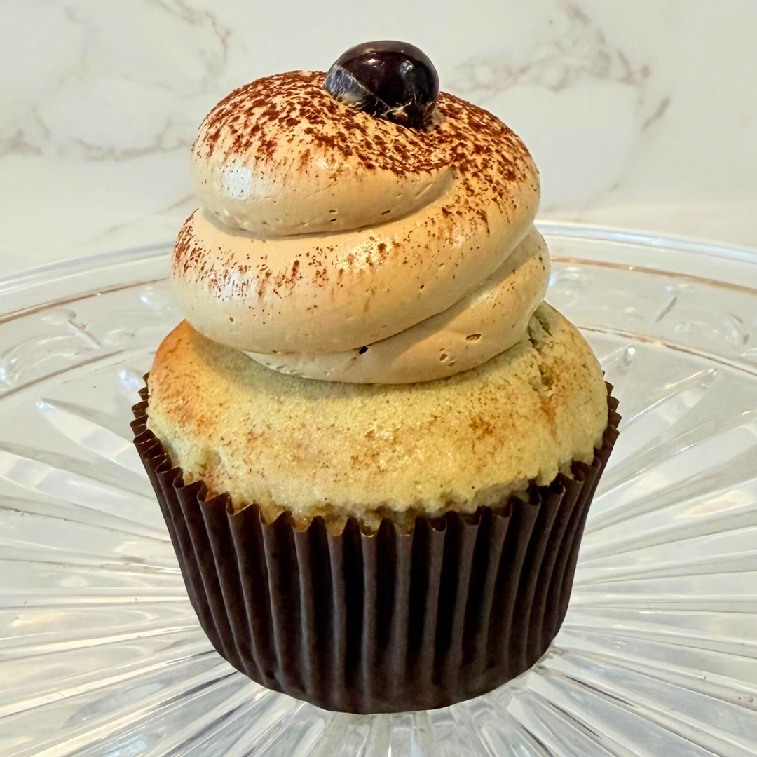 Cupcake with white and pale yellow icing in a dark brown cupcake liner