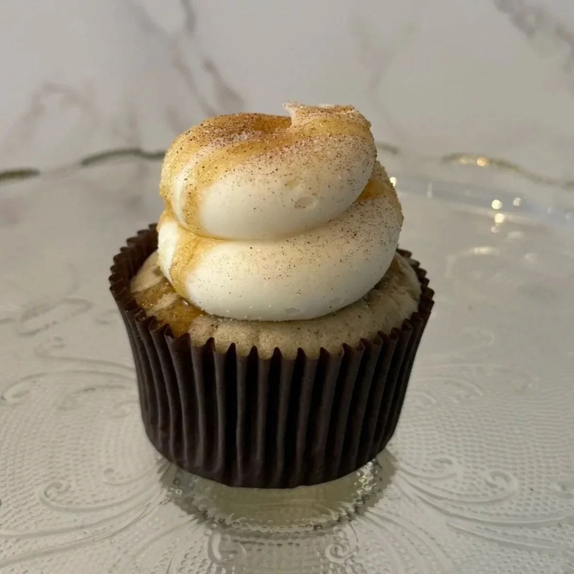 Close-up of a cupcake with brown cake base, topped with white frosting.