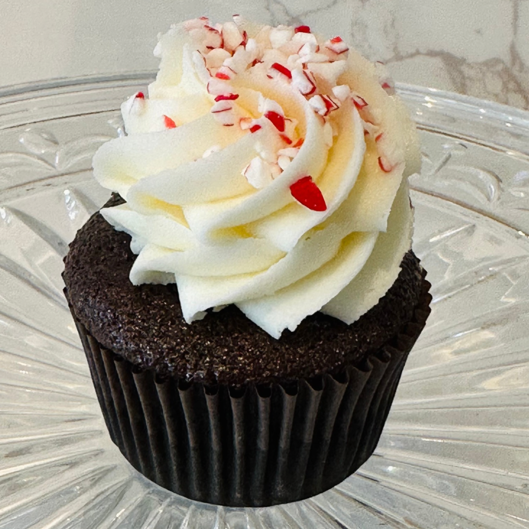 Cupcake with pink frosting topped with a small piece of candied ginger