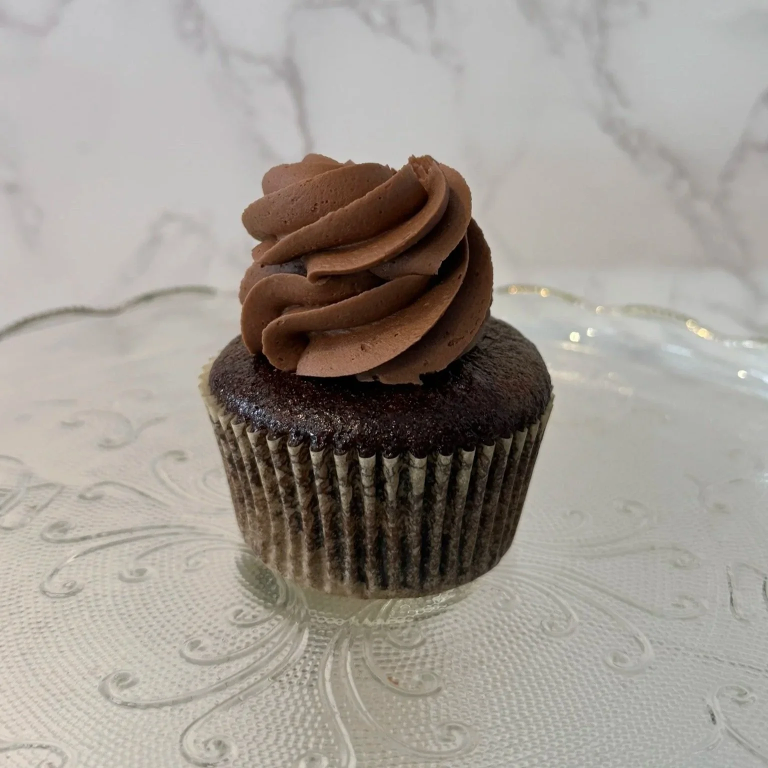 Cupcake with vanilla and chocolate frosting topped with a swirl of white frosting.