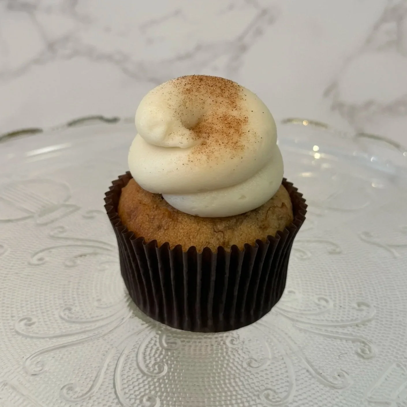 Cupcake with pink frosting topped with a small piece of candied ginger