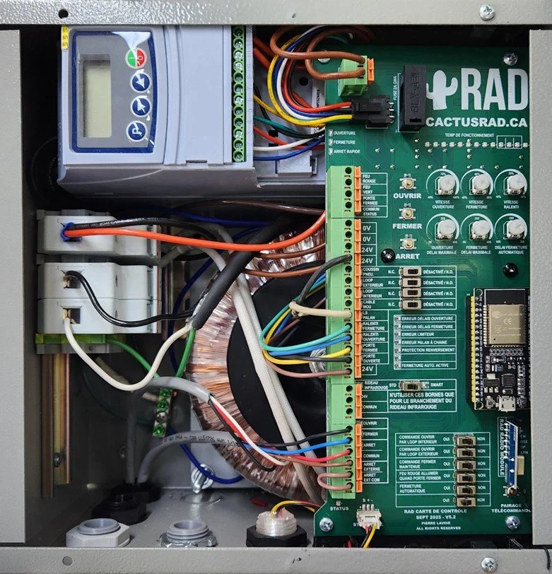 Un panneau électrique contenant un contrôleur de porte, un circuit imprimé de commande et divers câbles et composants électroniques.