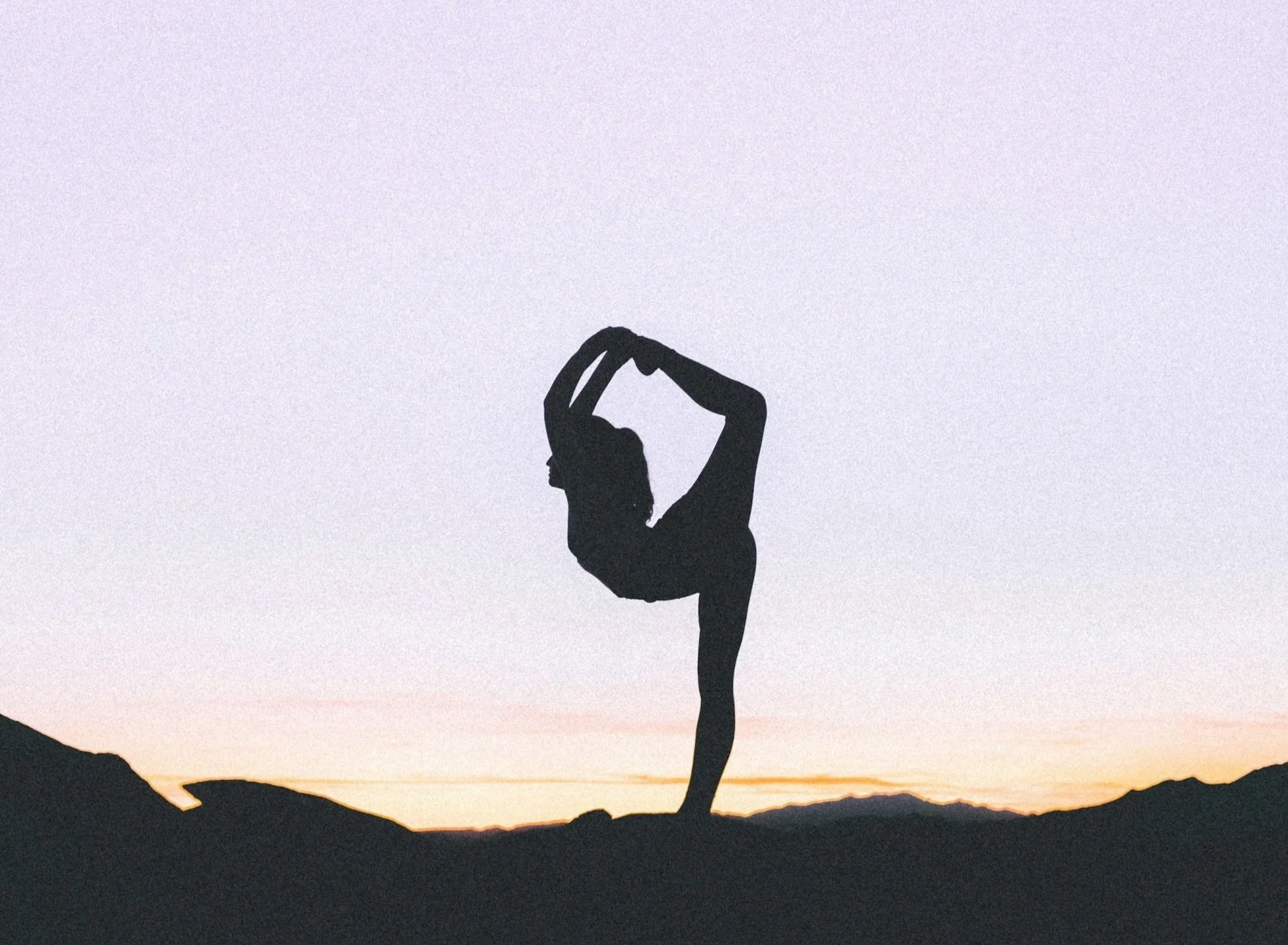 Woman in yoga dancer pose on mountain at sunset. True Naturals relaxing muscle rub.