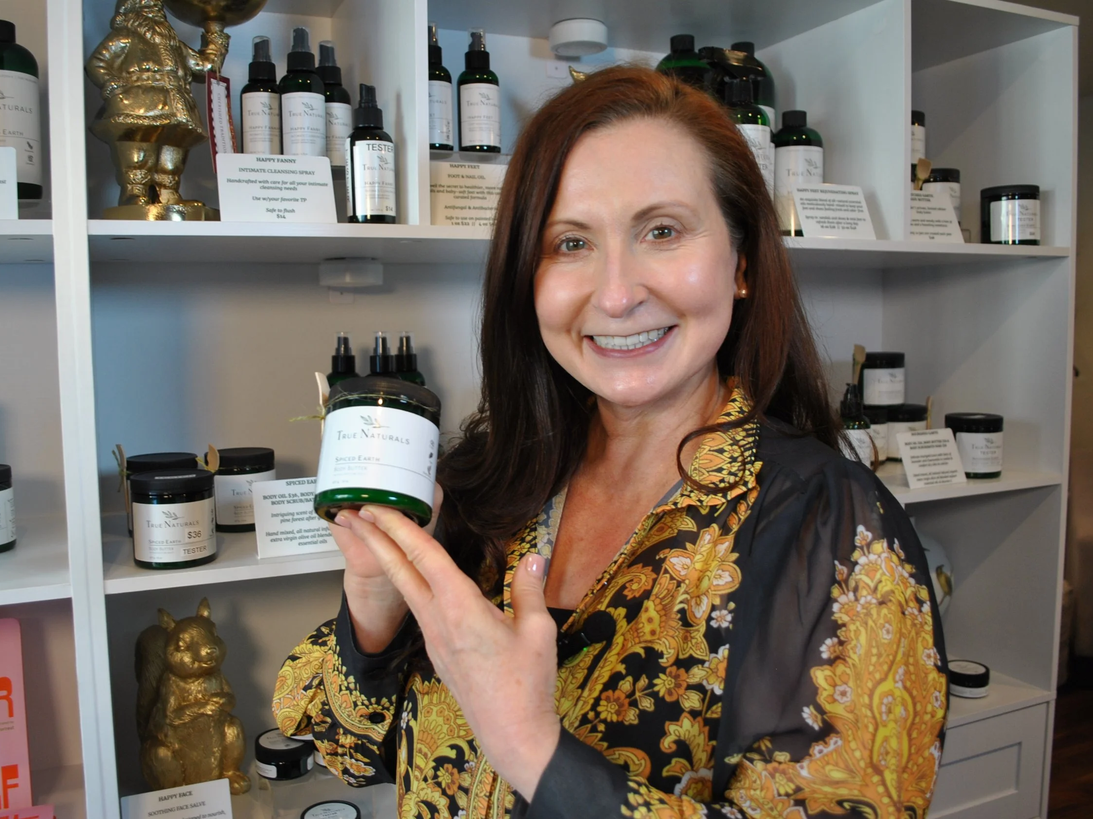 Kris, Founder of True Naturals, at the True Naturals store holding body butter