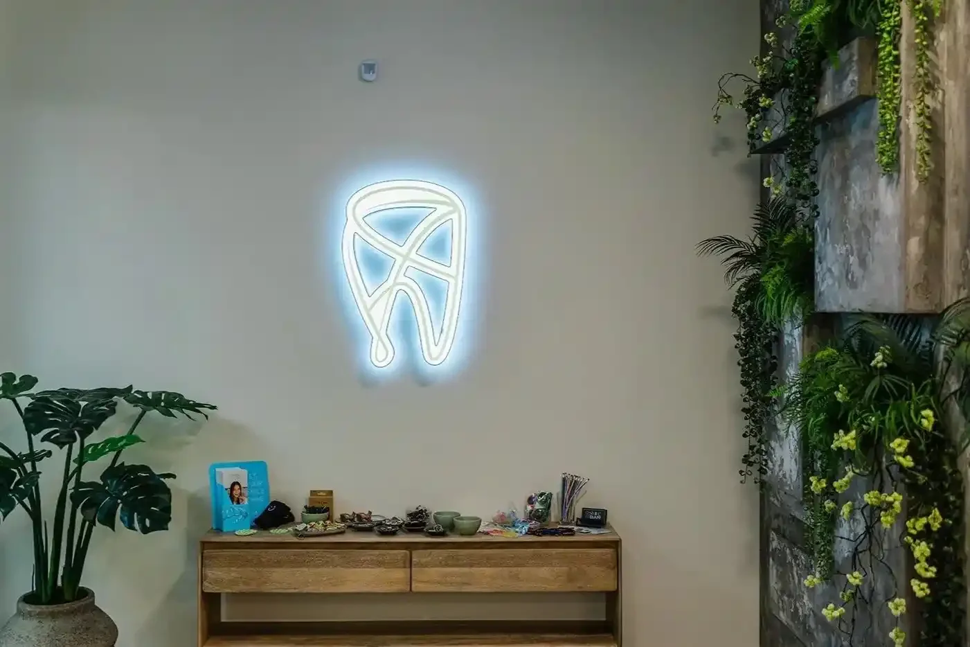 Dental care products displayed on a wooden console beneath a neon tooth sign at Smile Bar in Calgary.