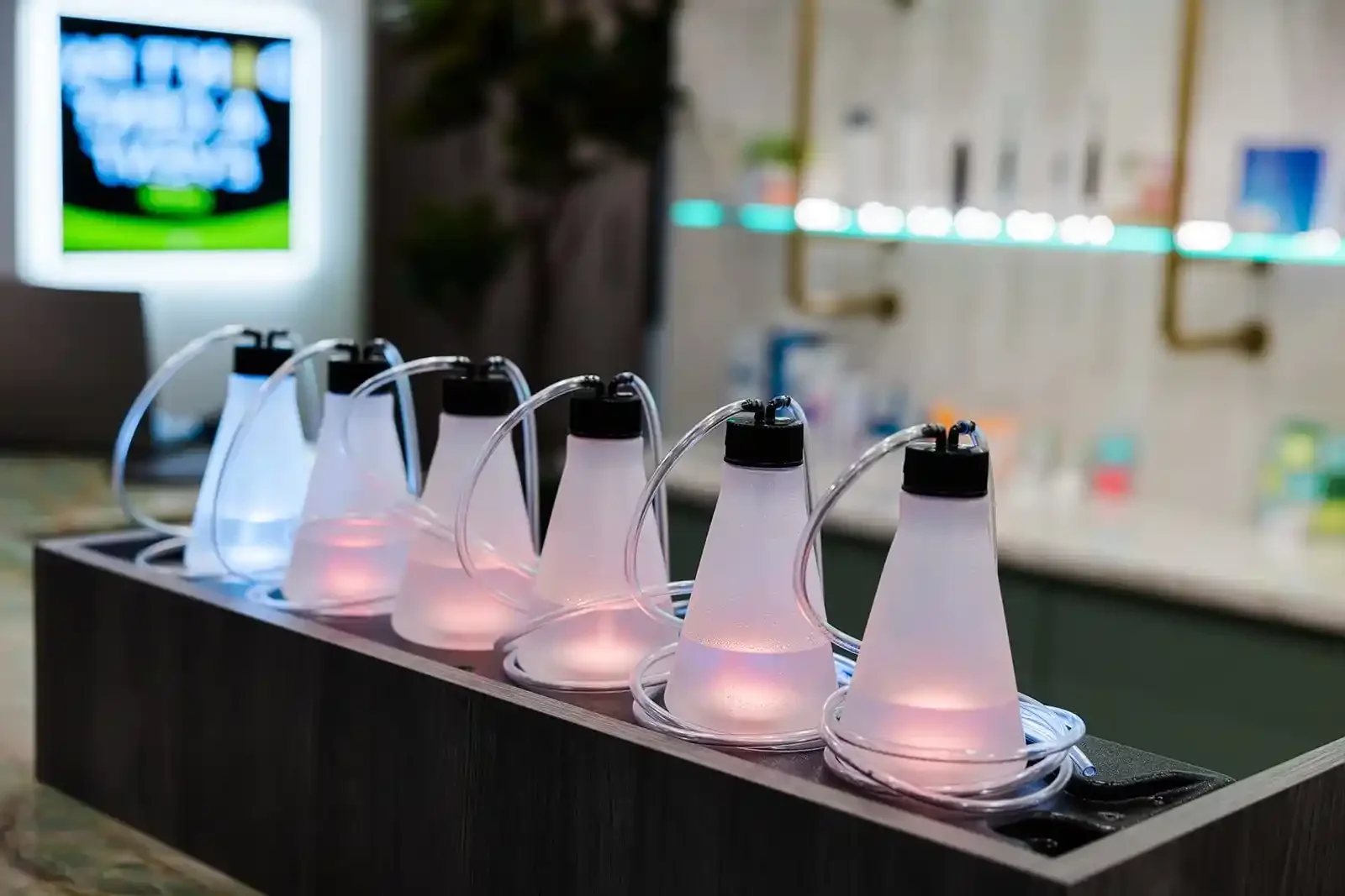 A row of illuminated glass flasks and tubing at the oxygen bar inside Smile Bar in Calgary.