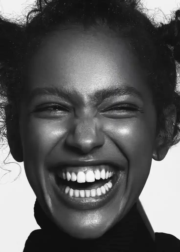 Close-up black and white portrait of a laughing woman displaying bright white teeth, representing teeth whitening services at Smile Bar in Calgary.