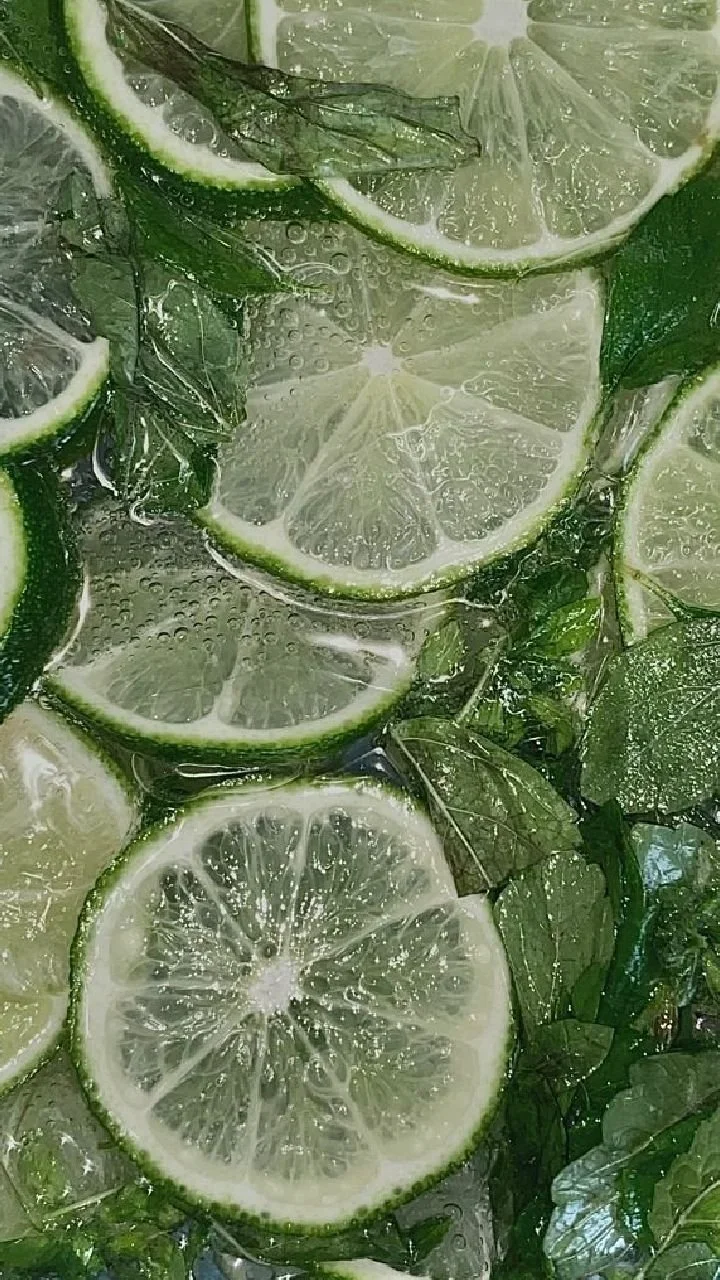 Close-up of sliced limes and mint leaves in water.