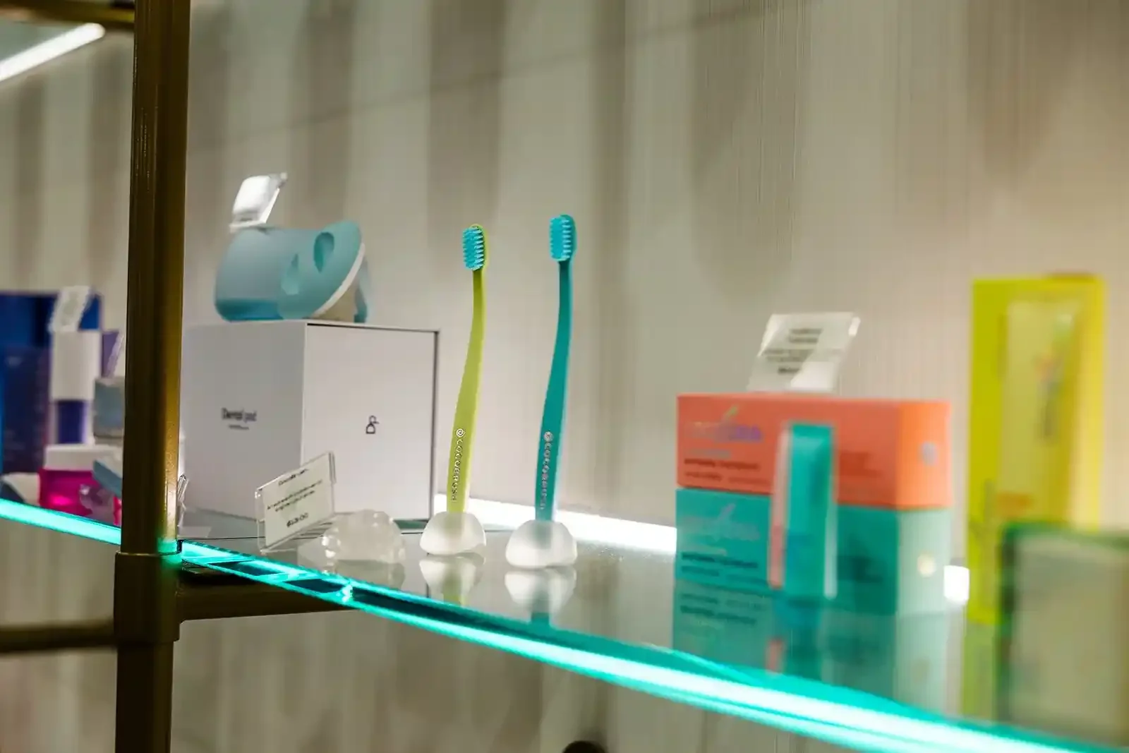 Illuminated glass shelf displaying premium dental care products, including upright toothbrushes, at Smile Bar in Calgary.