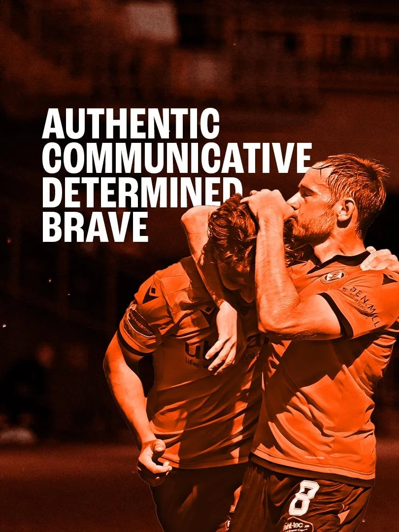 Two male Dundee United players celebrating on a sports field, with one embracing the other.