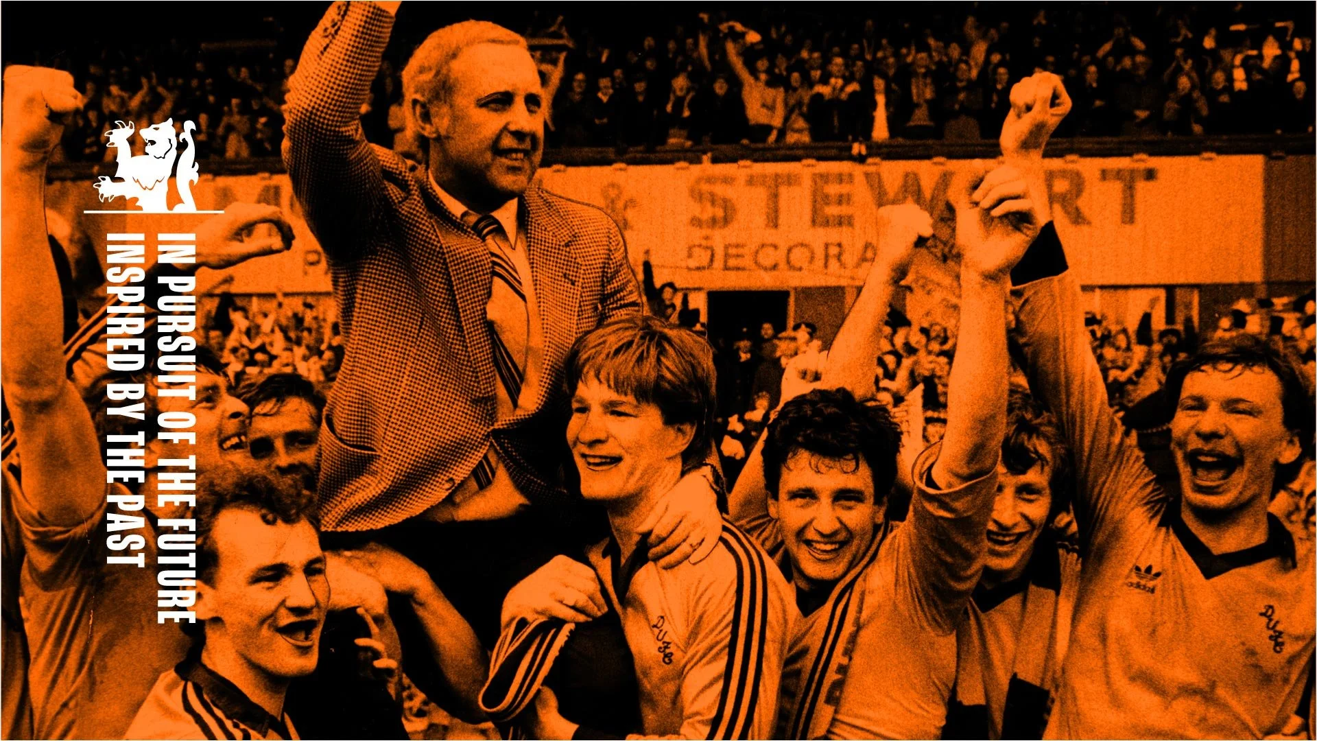 A group of football players celebrating on a sports field, with a man being lifted by others. The group is joyous, raising their fists. Text overlay says "In Pursuit of the Future Inspired by the Past".
