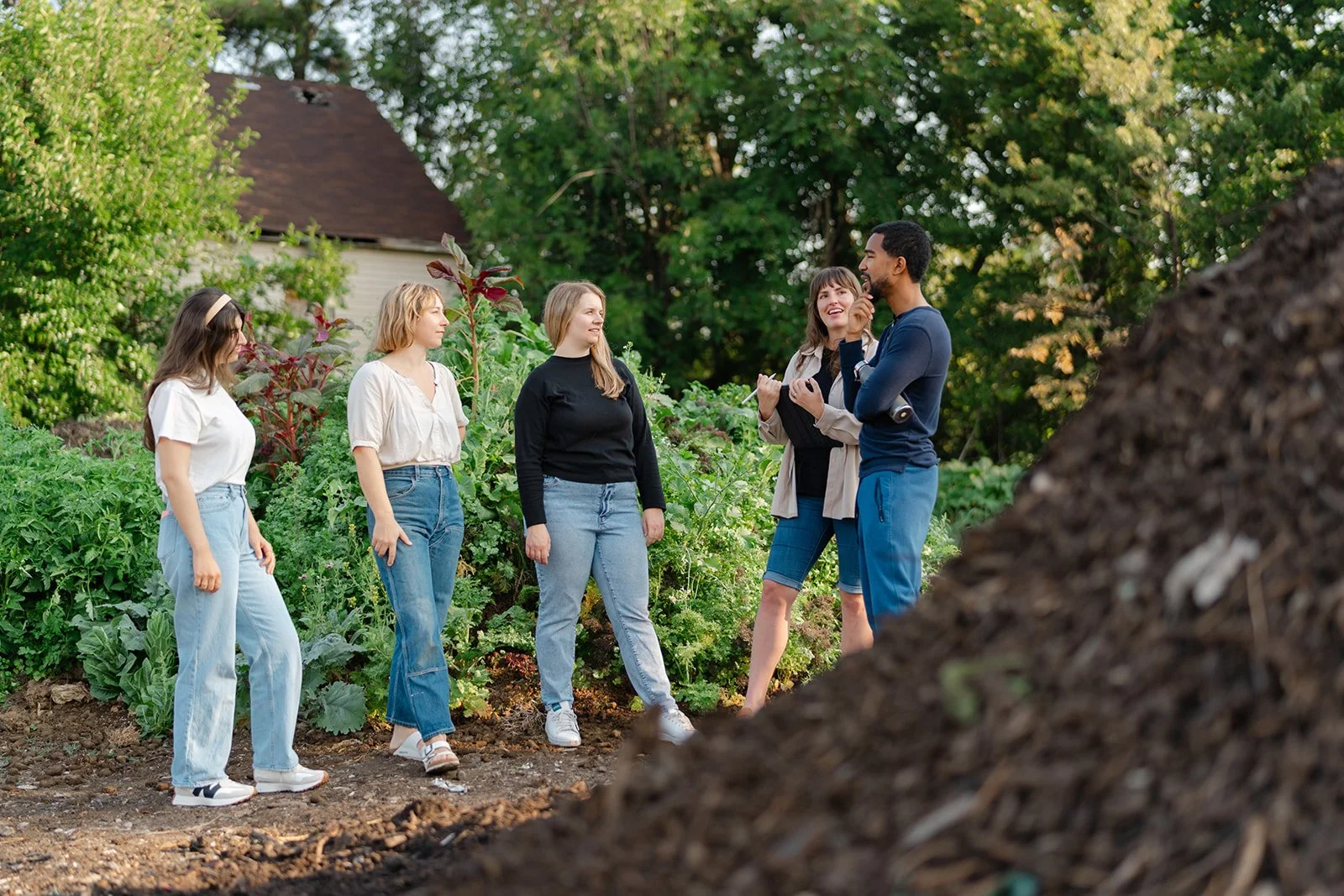 A group of people on a farm near a pile of compost