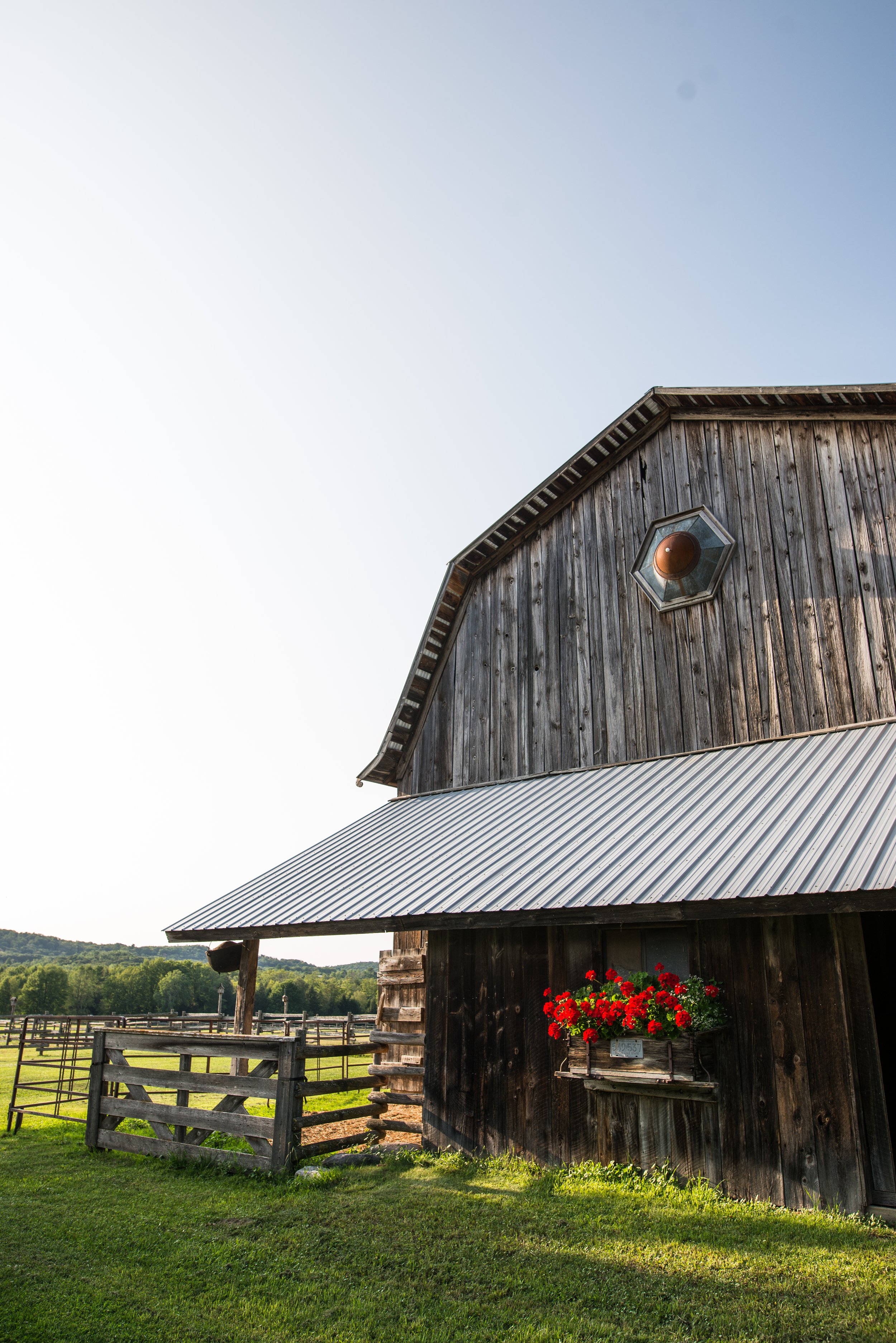 A wooden barn with pastures in the background